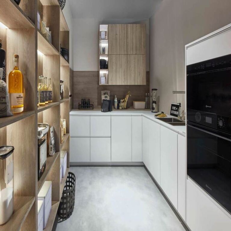 Moderne weiße Küche mit Hochschränken, Holzregal und schwarzen Einbaugeräten – Küche kaufen Oldenburg
